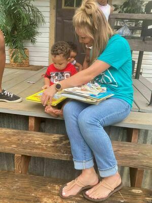 A Rusk Elementary School teacher visits with a toddler Aug. 2, sharing a handful of books as part of a project designed to foster a love for reading that ultimately creates bonds between students, their families and the school staff. 

Courtesy photo